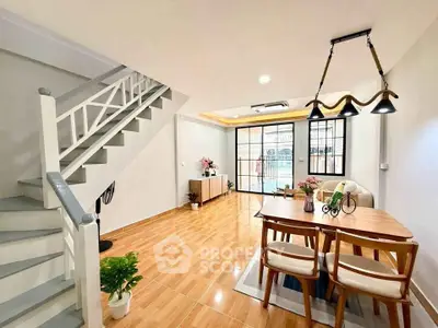 Stylish open-plan living and dining area with modern decor and staircase.