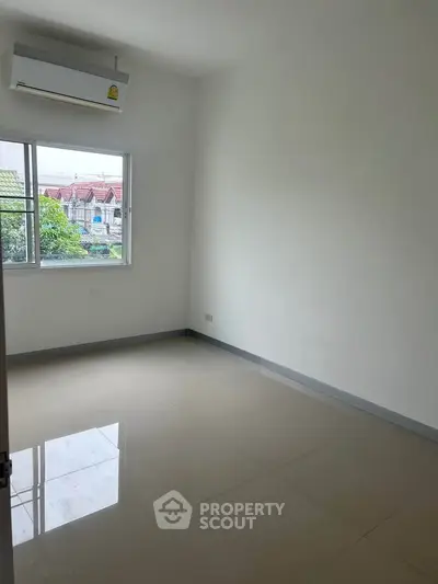 Spacious empty room with large window and air conditioning, perfect for customization.