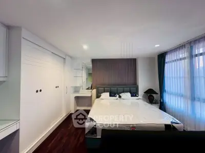 Spacious bedroom with elegant decor and large windows for natural light.