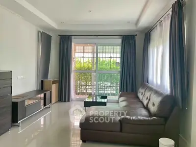 Spacious living room with modern leather sofa and large windows offering natural light.