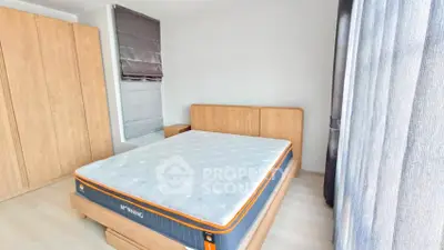Spacious bedroom with modern wooden furniture and large window for natural light.
