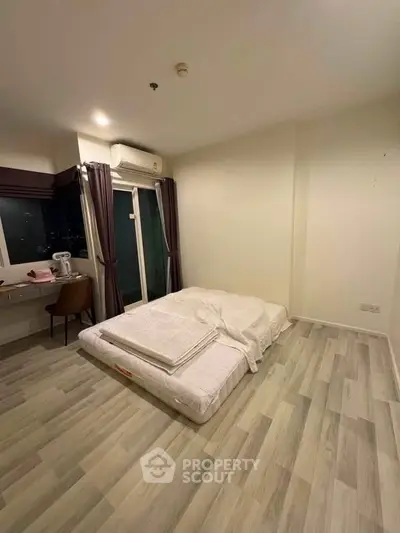 Spacious bedroom with minimalist decor and large window for natural light.