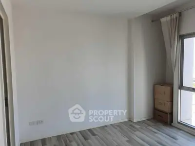 Spacious empty room with large window and wooden flooring, perfect for customization.