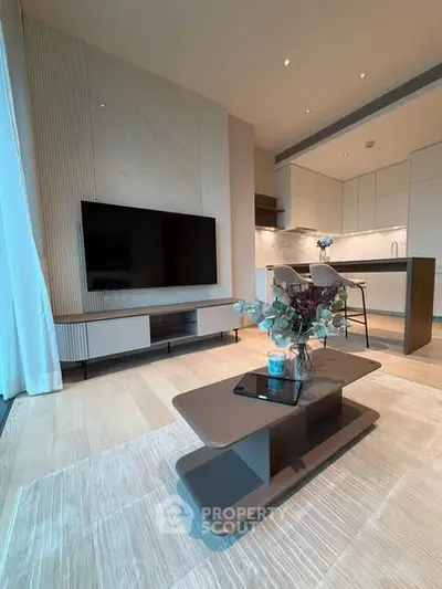 Modern living room with sleek design and open kitchen layout, featuring a large TV and stylish coffee table.
