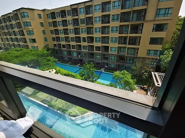 Stunning view of modern apartment complex with pool from balcony window.