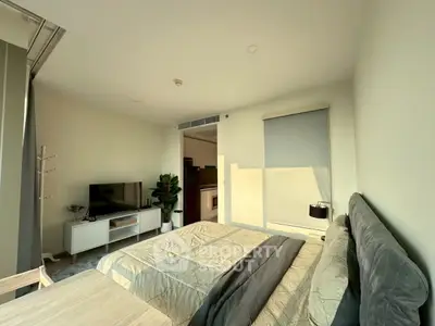 Modern bedroom with cozy bed, TV, and natural light in stylish apartment.