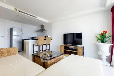 Modern open-plan living room with kitchen, featuring wicker furniture and sleek appliances.