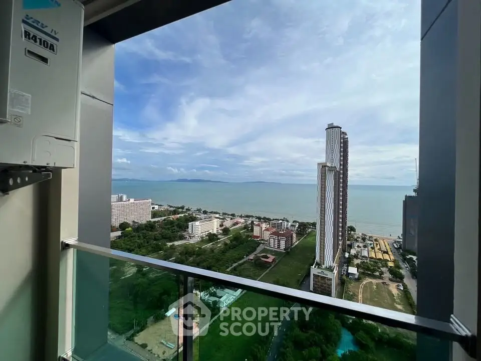 Stunning high-rise balcony view overlooking ocean and cityscape, perfect for urban living.