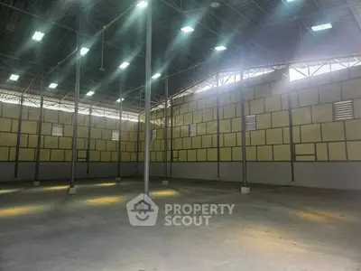 Spacious industrial warehouse with high ceilings and ample natural lighting.