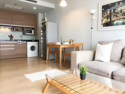 Modern open-plan living room with kitchen, featuring sleek furniture and stylish decor.