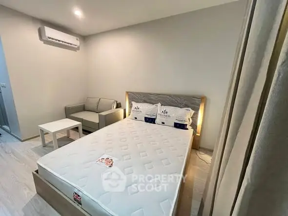 Modern bedroom with cozy sofa and air conditioning in stylish apartment.