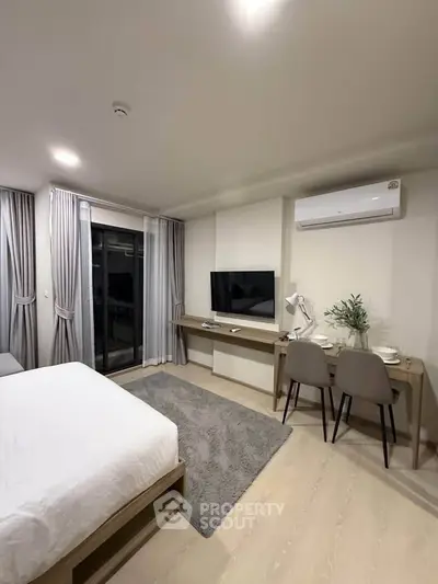 Modern bedroom with balcony access, featuring sleek furniture and a cozy ambiance.
