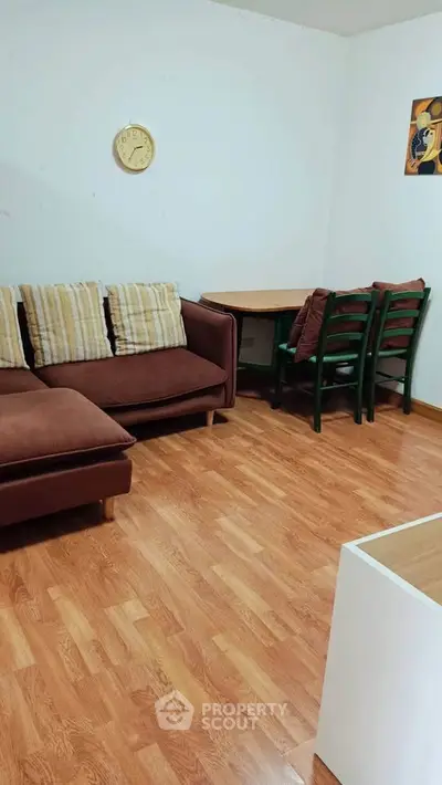 Cozy living room with wooden flooring, comfortable sofa, and a small dining area.