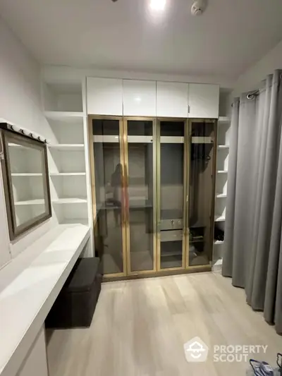 Modern walk-in closet with glass doors and ample shelving in a stylish home.