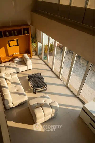 Luxurious spacious living room with modern white sofas and large windows offering abundant natural light.