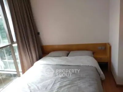 Cozy bedroom with large window and modern furnishings in a bright apartment.