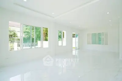 Spacious bright living room with large windows and glossy white flooring.