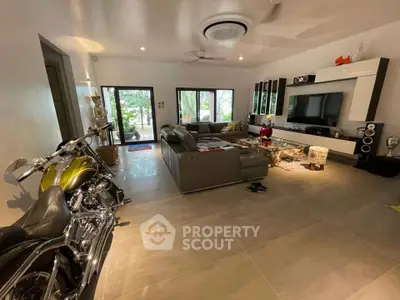Spacious living room with modern decor and motorcycle, featuring large windows and entertainment center.