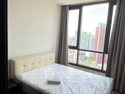 Modern bedroom with large window offering stunning city view in high-rise apartment.