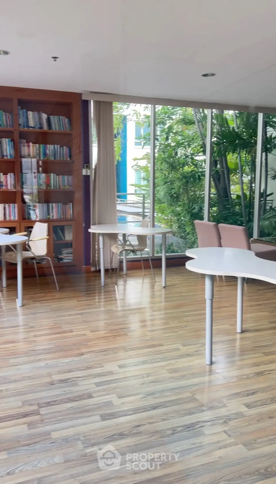 Spacious library with modern furniture and lush garden view, perfect for study or relaxation.