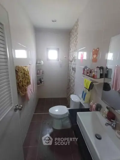 Compact bathroom with modern fixtures and decorative tiles, featuring a window for natural light.