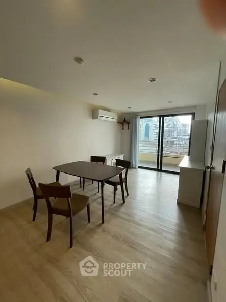 Spacious dining area with city view and balcony access in modern apartment.