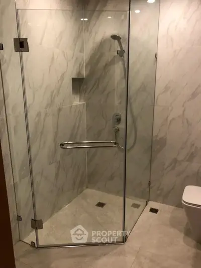 Modern bathroom with glass shower enclosure and marble tiles