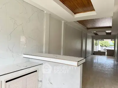 Spacious modern interior with marble accents and wooden ceiling details.