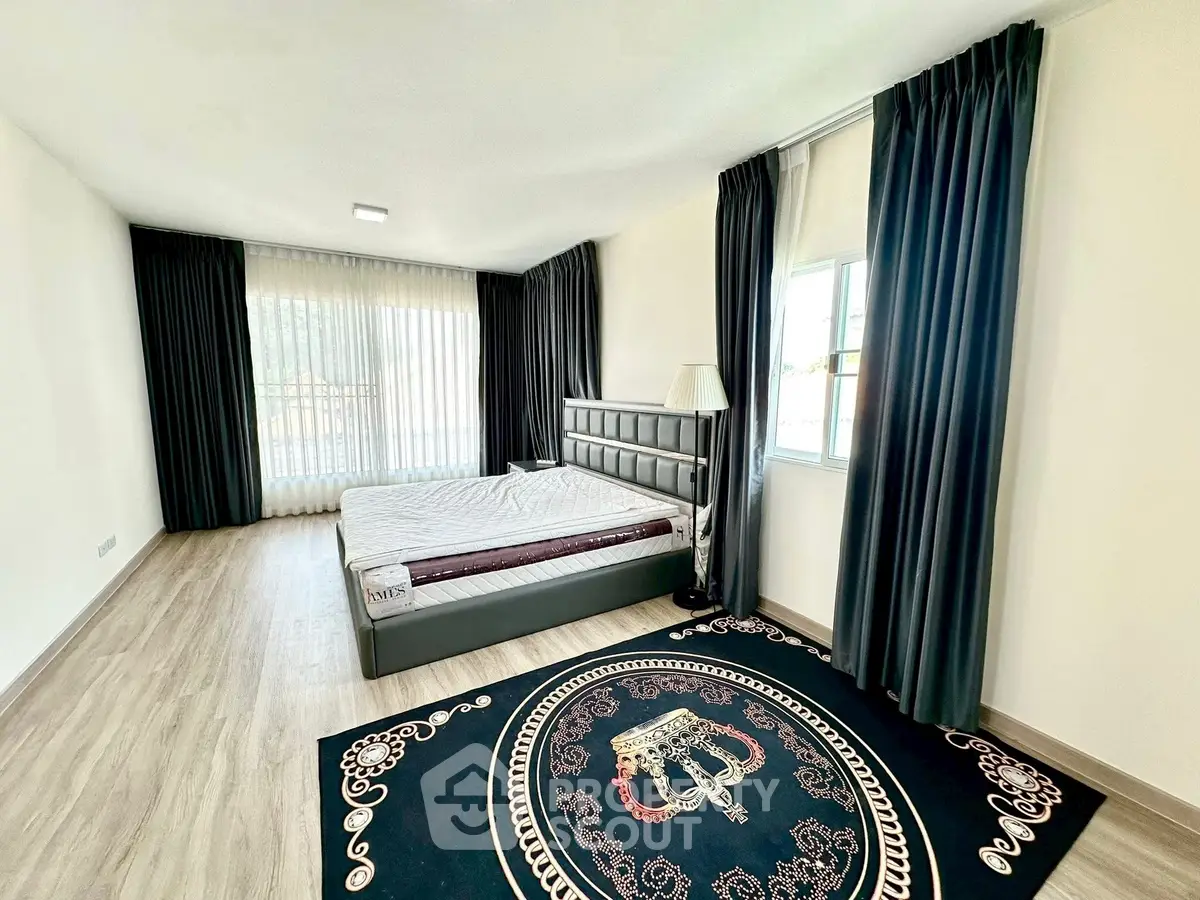 Spacious bedroom with elegant decor and large windows for natural light.