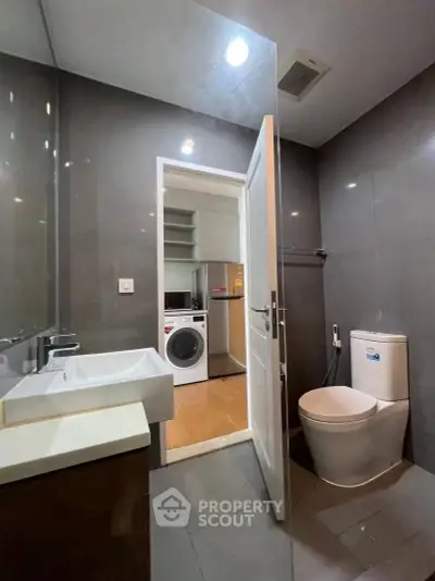 Modern bathroom with sleek design and adjacent laundry area featuring a washing machine.