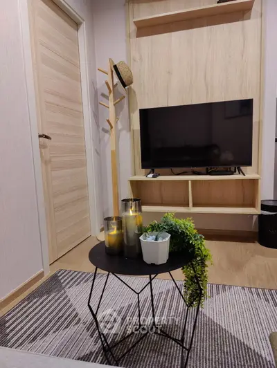 Modern living room with stylish decor, featuring a flat-screen TV, wooden accents, and cozy lighting.