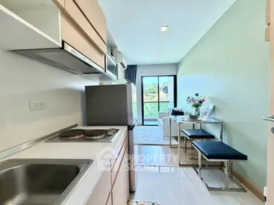Modern studio apartment with compact kitchen and bright living area overlooking greenery.