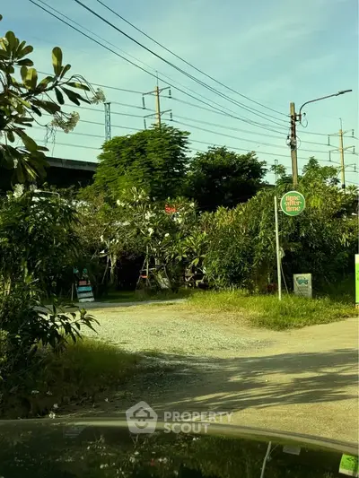 Charming garden entrance with lush greenery and clear blue sky, ideal for nature lovers.