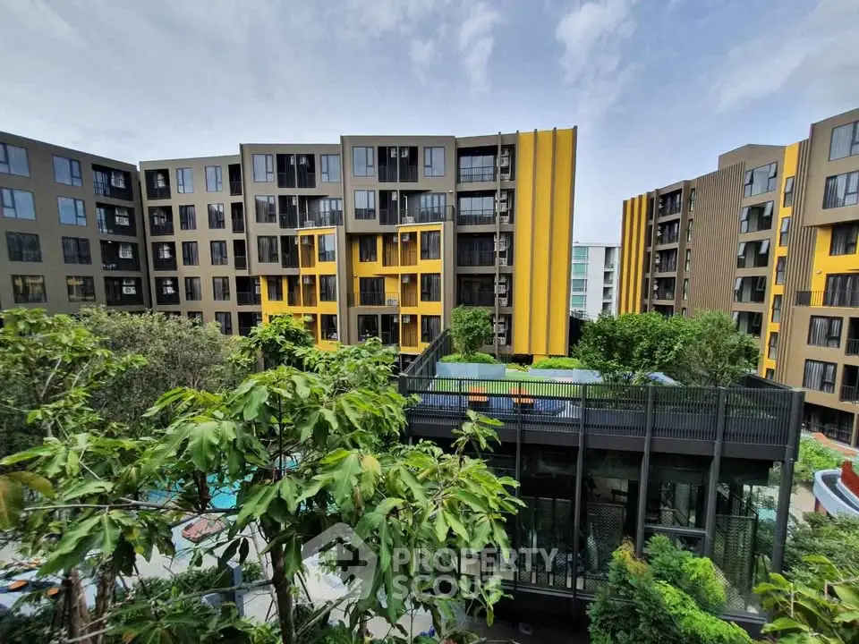 Modern apartment complex with vibrant yellow accents and lush greenery