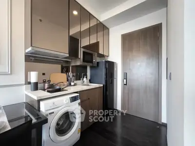 Modern compact kitchen with sleek cabinets and built-in appliances, featuring a washing machine and microwave.
