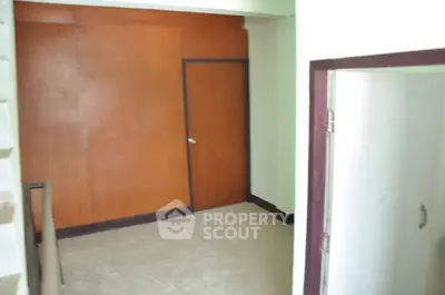 Spacious interior with wooden door and tiled floor, ideal for versatile use.