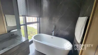 Luxurious bathroom with modern freestanding bathtub and large window view.