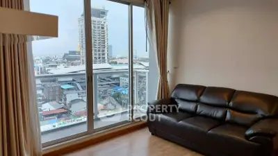Modern living room with city view and leather sofa in high-rise apartment.