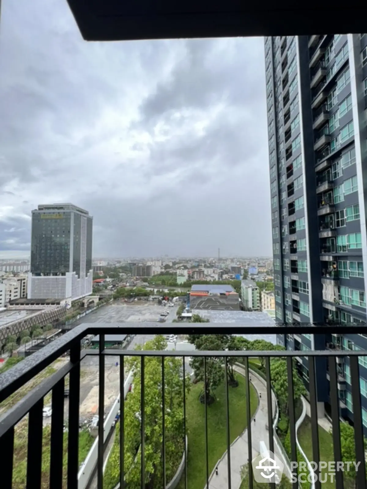 Stunning cityscape view from high-rise balcony with modern architecture and lush greenery.