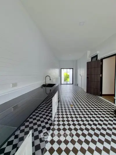 Sleek modern kitchen with black and white checkered floor and glossy countertops, leading to a bright window view.