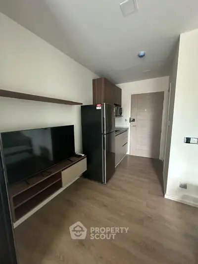 Modern compact kitchen with sleek appliances and wooden flooring in a cozy apartment.