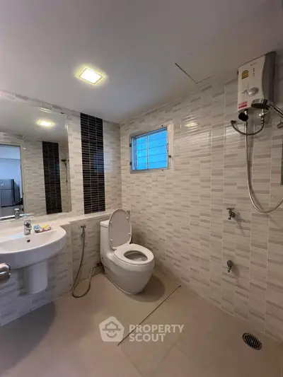 Modern bathroom with sleek tiles and shower heater, perfect for comfort and style.