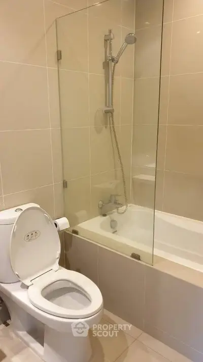 Modern bathroom with bathtub and shower in sleek beige tiles.
