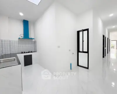 Modern minimalist kitchen with sleek white cabinetry and gas stove in open layout apartment.