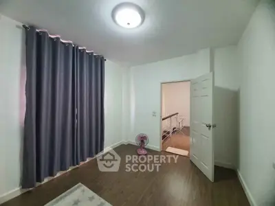 Spacious bedroom with wooden flooring and elegant curtains