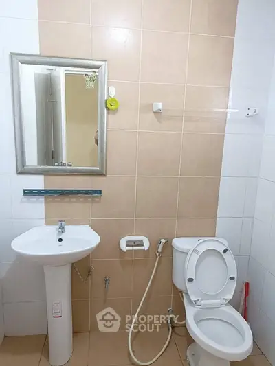 Modern bathroom with sleek fixtures and neutral tiles, featuring a pedestal sink and toilet.