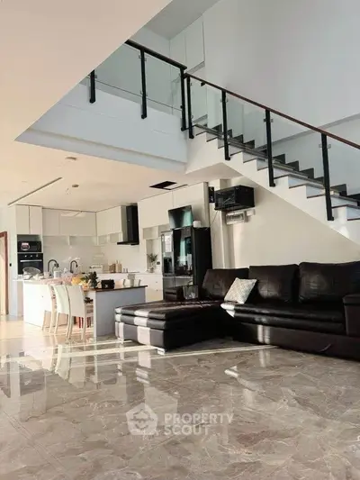 Spacious modern living room with open kitchen and sleek staircase in luxurious home.