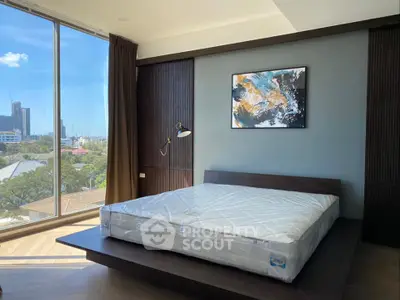 Modern bedroom with large window and city view, featuring stylish decor and natural light.