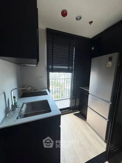 Modern kitchen with sleek black cabinetry and large window offering city view