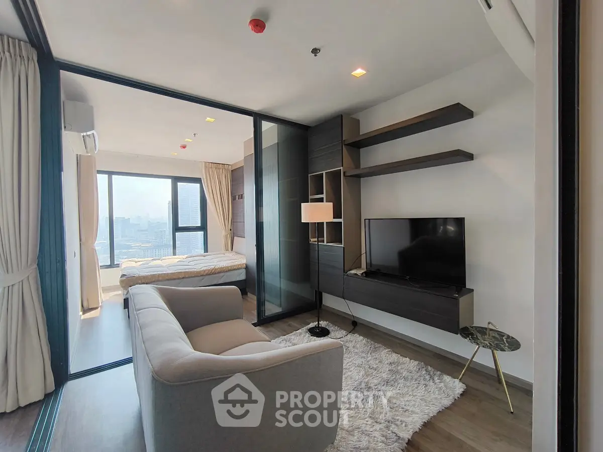 Modern living room with cozy sofa and TV, adjacent to a bedroom with city view.